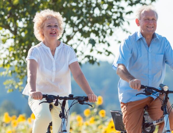 casal de idosos andando de bicicleta em um campo de flores aberto